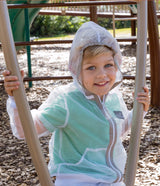 A small child sits on a playground swing. He's wearing a ShrugBug jacket with the hood up.